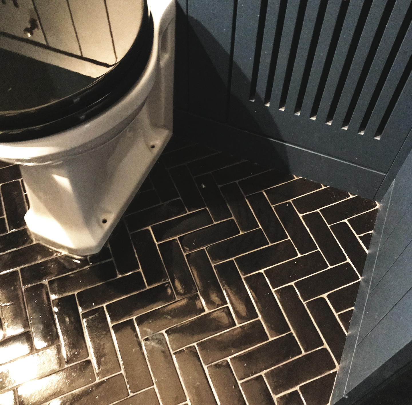 Floor detail in cloakroom, encaustic herringbone tiles in black, bespoke cabinetry in F&B Hague Blue