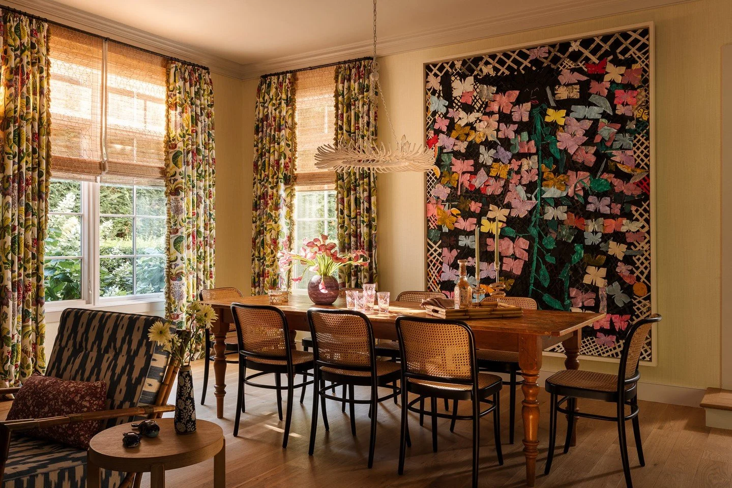 A step down from the stair hall leads into the dining room, where ceiling height and natural light expand the sense of space. Windows frame views of tall hedges and the lower-level patio beyond, balancing privacy with openness. Designed in collaborat