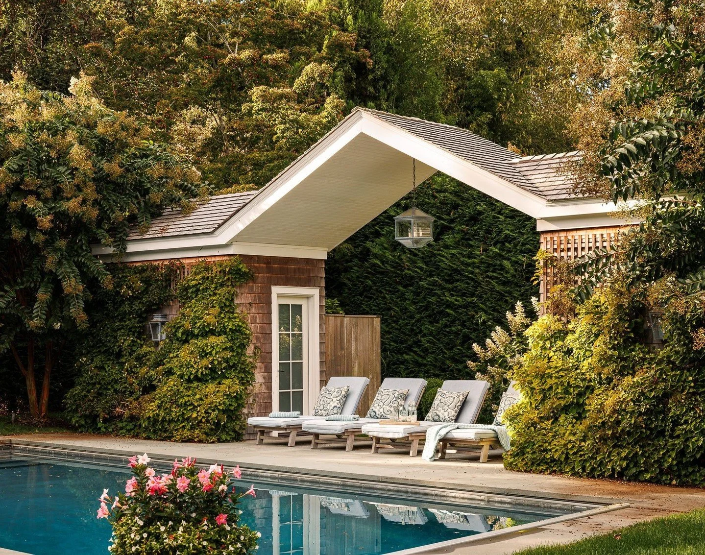 The pool cabana&mdash;two modest volumes joined by a centered gable&mdash;anchors the far end of the property, perfectly aligned on axis with the main residence and pool. One side conceals equipment and a bath, the other discreet storage, all wrapped