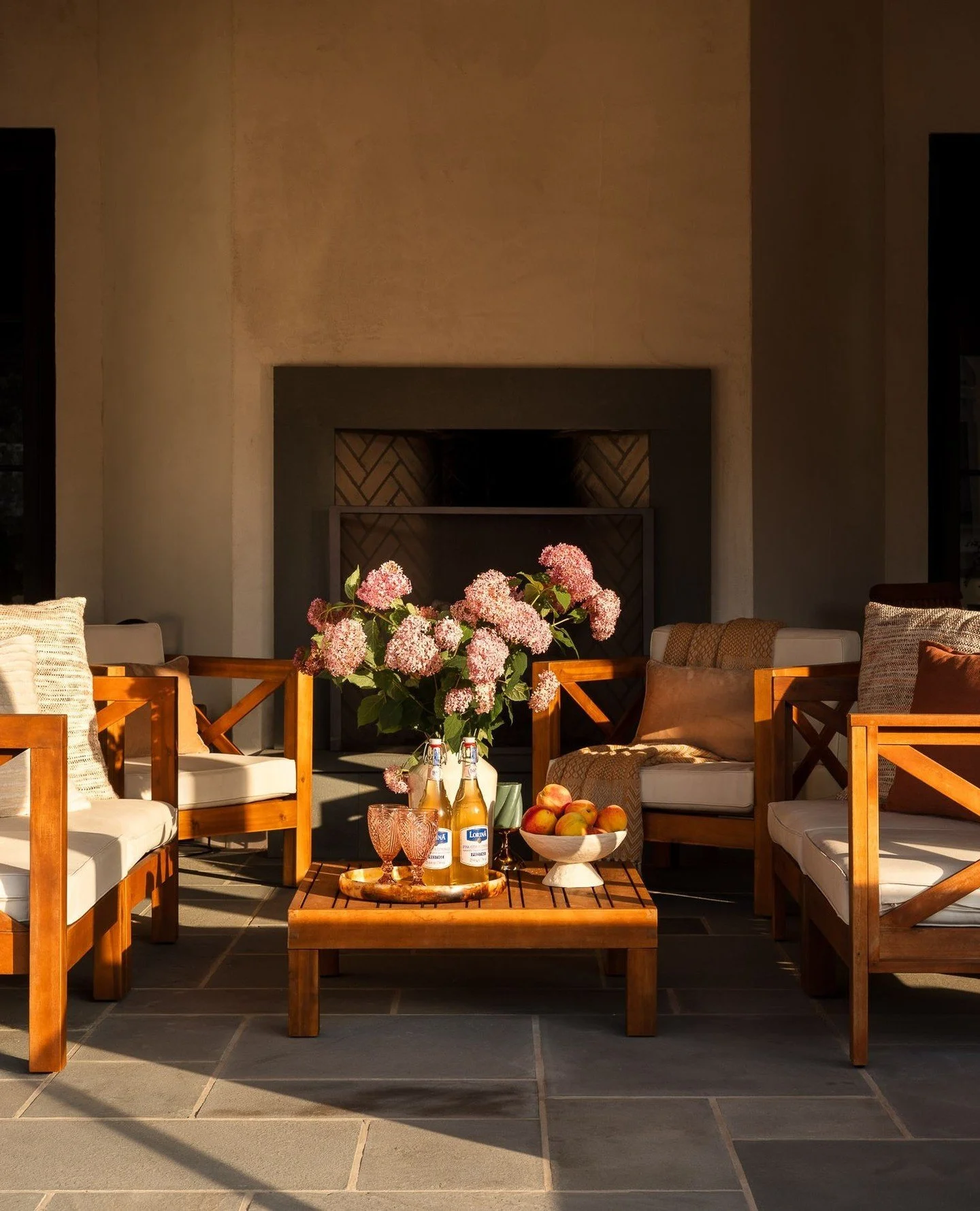 Evening light washes across the terrace, illuminating the double-sided fireplace and the thoughtful details that bring the space to life. The home&rsquo;s authentic cement stucco brings a true old-world texture and depth to its otherwise simple massi