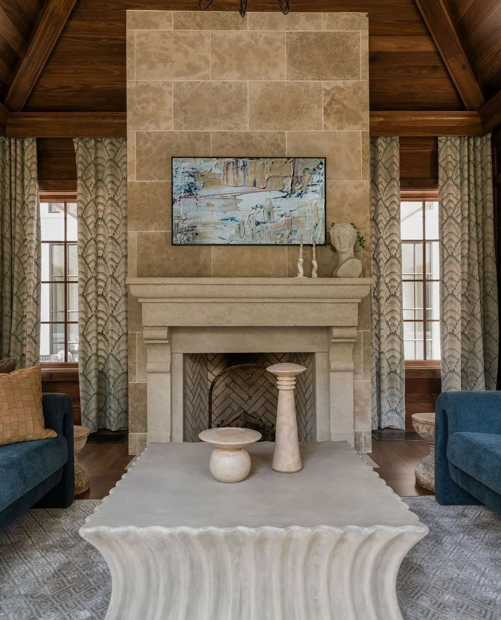 A stone fireplace designed as the true anchor of the room.⁠
Clad in natural stone and framed by warm wood ceilings, it brings balance, scale, and a sense of permanence to the space&mdash;quietly grounding the architecture while inviting gathering and