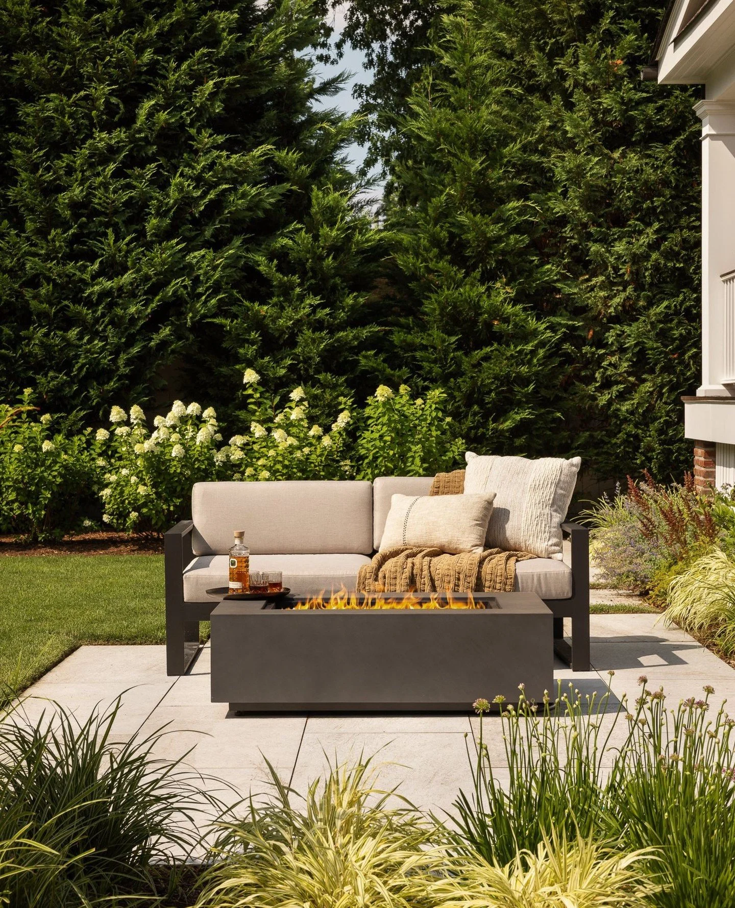 A new firepit lounge, designed by Scenic Landscaping in collaboration with RS Mannino, sits just beyond the covered porch to extend outdoor living. Framed by layered plantings and tall evergreens for privacy, it&rsquo;s a space made for evenings gath