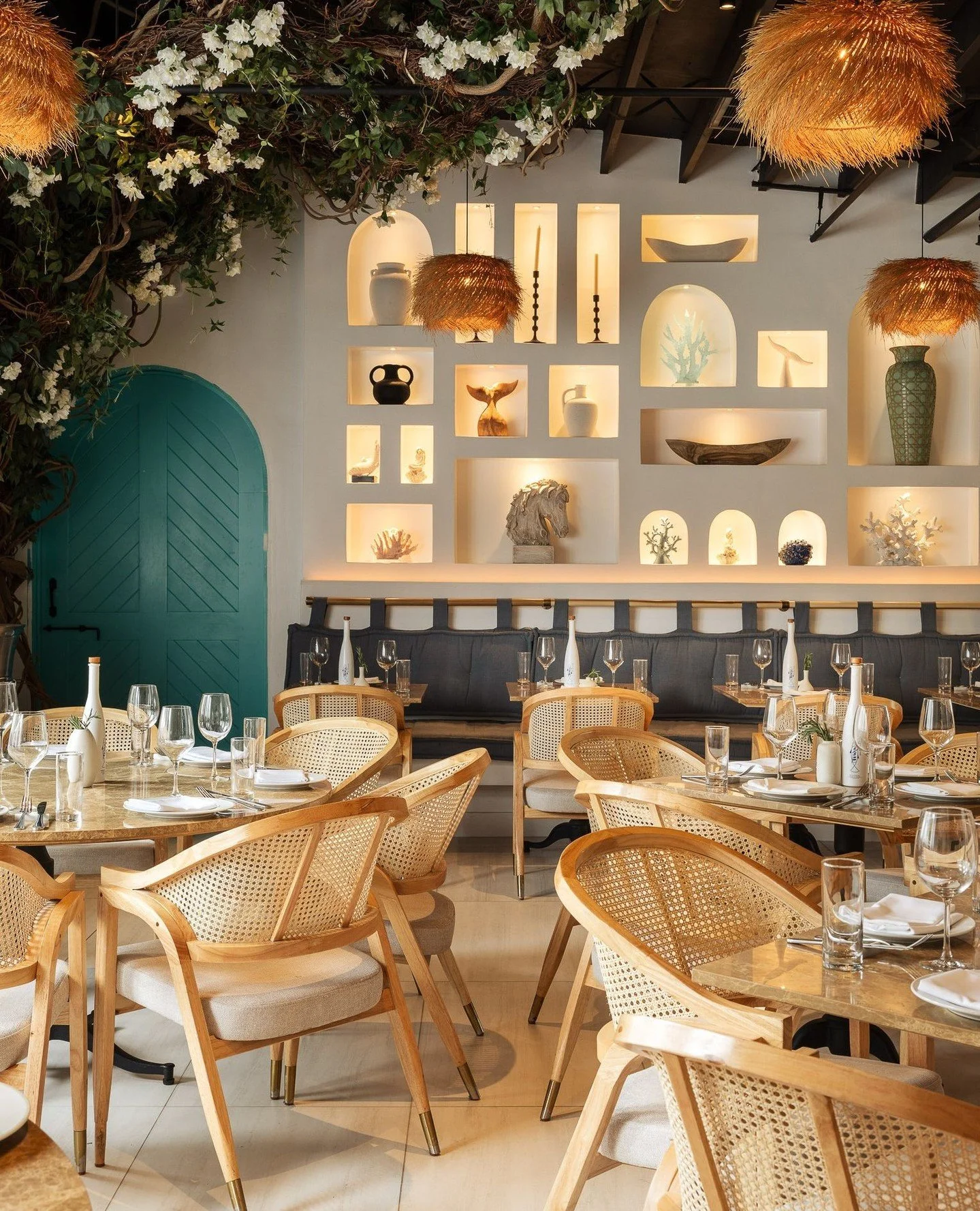 A saturated blue door punctuates the neutral palette, subtly referencing the Greek coastline without becoming literal. The illuminated niches create depth, balancing color with architectural clarity.⁠
⁠
Photography by @mikevantassell⁠
⁠
#TrataRestaur