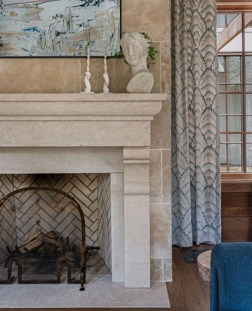 A study in proportion and permanence. The limestone fireplace anchors the room with quiet authority&mdash;layered against hand-set stone, framed by rich walnut paneling, and softened by tailored drapery. A hearth designed not just as a focal point-bu