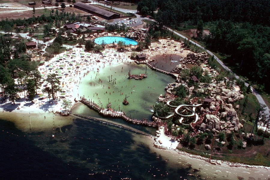 Bay Cove pool with its dam separating the park from Bay Lake. Bay Cove had a sand bottom and included a tire swing, boom swing, rope climb, and T-bar drop. (Photo: ©Disney)