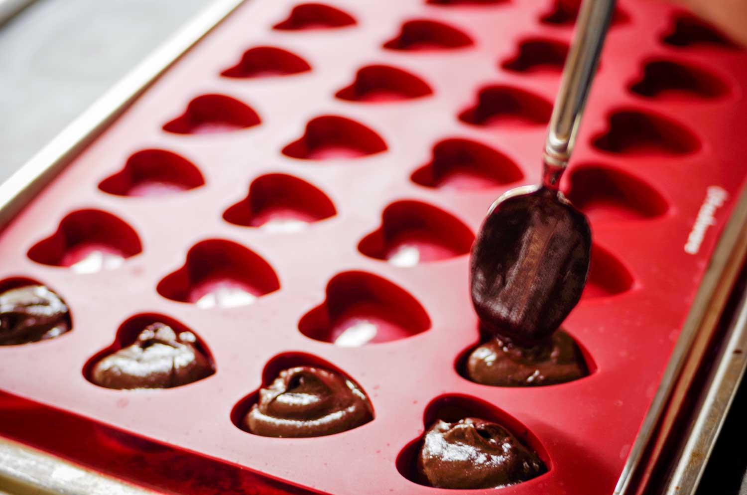 Putting chocolate into heart mold.