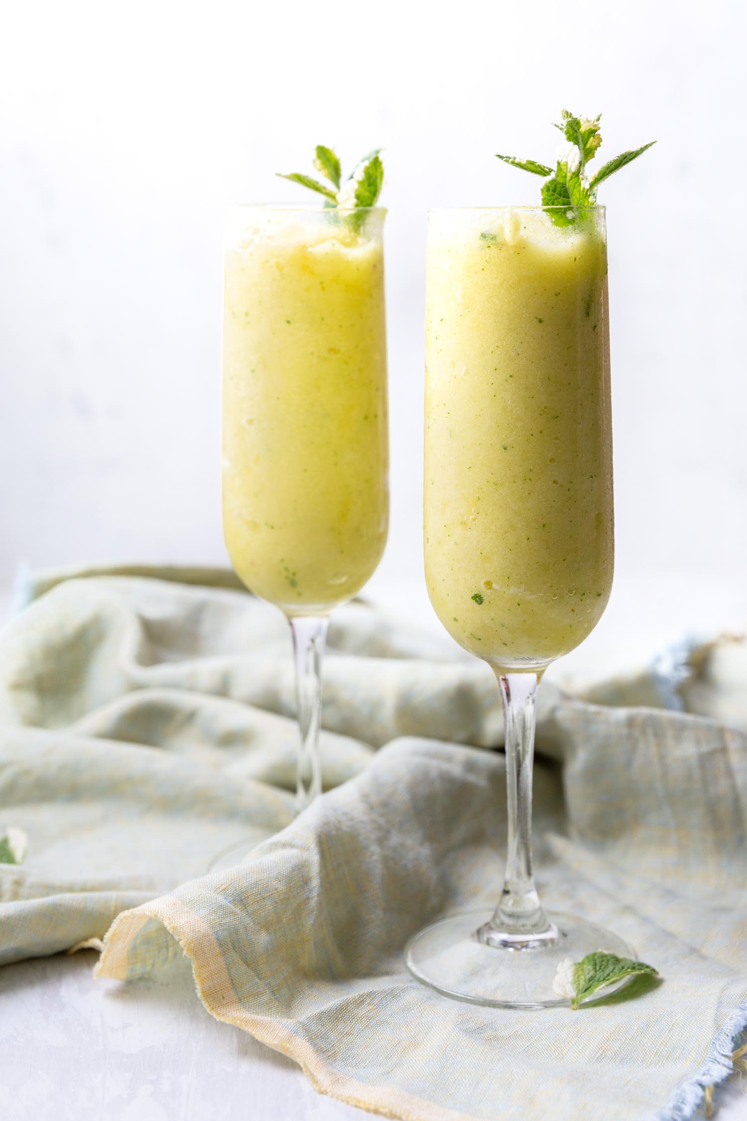 Pineapple Mint Frozen Drinks require just two ingredients (+ water) for a delicious and refreshing mocktail - add your favorite spirits for the ideal summery cocktail. #summerdrink #summercocktail #cocktail #pineapple #pineapplemintrecipe #drinkrecipe #frozendrink #blended #mocktail #fruitydrink #tropicaldrink #mojito