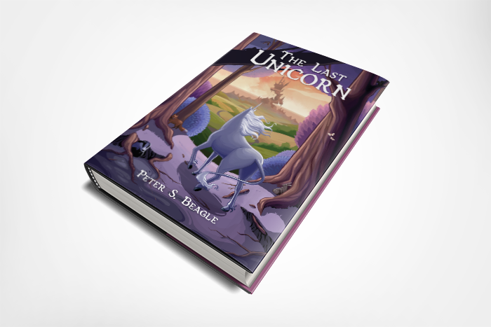  A book laying at three-quarter view on a white field. The book is “The Last Unicorn” by Peter S. Beagle. The cover shows a unicorn looking out of the lilac wood towards a crumbling castle on  the horizon. 