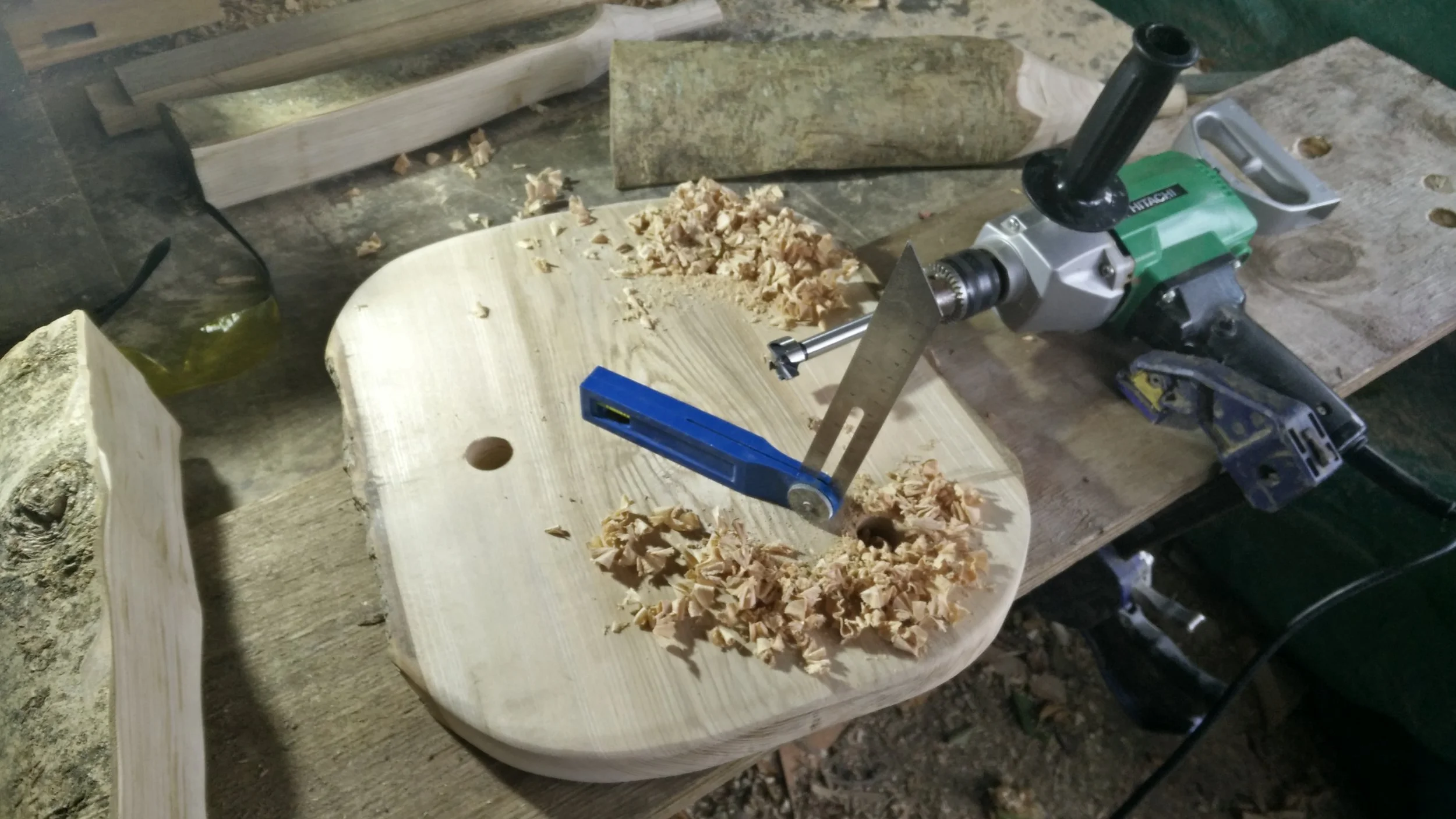 Next use an adjustable bevel to help you to drill 1” diameter holes at the same angle. The picture shows the holes being drilled from the underside of the stool top, angled so that the stool legs splay outwards