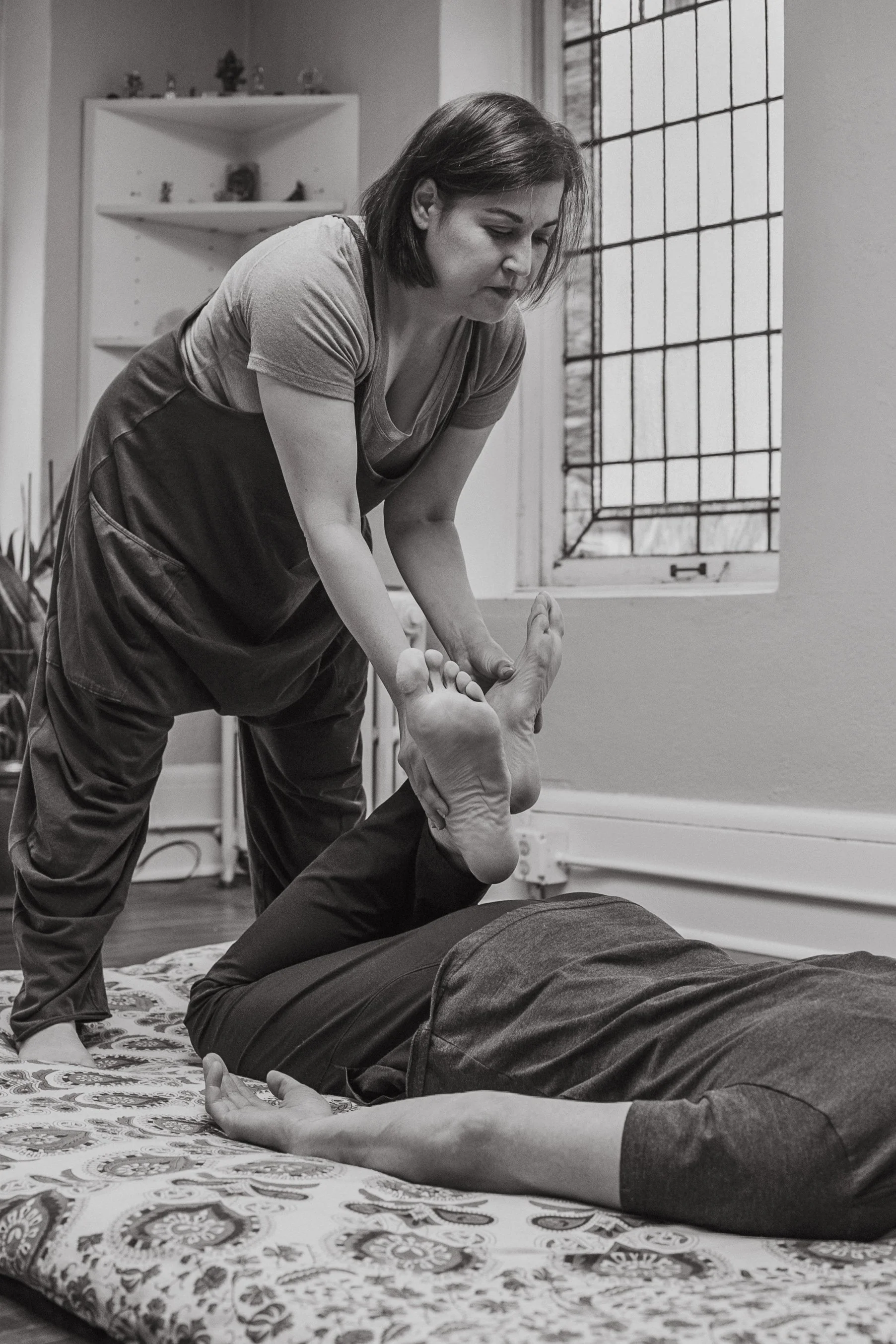 Kat Duvic practicing Thai Yoga Bodywork with a client on the floor in her Linden Hills Studio.