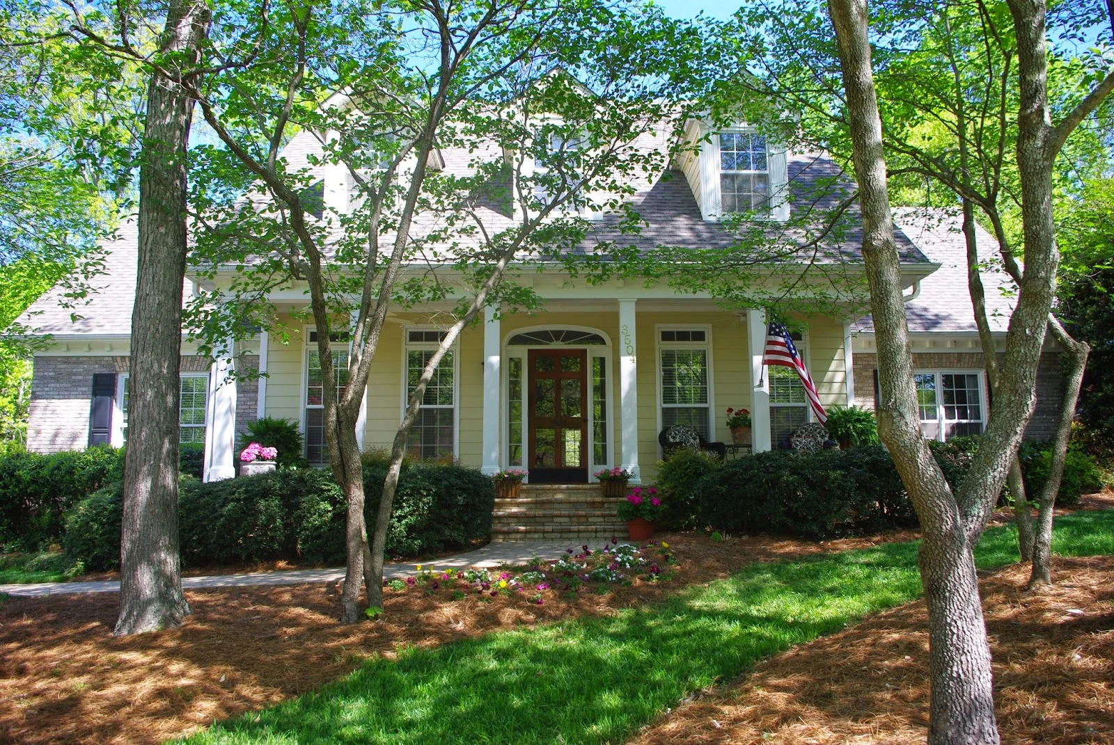 For this home, existing shrubs were pruned, sod, annuals and fresh pine needles added and colorful pots at the door to instant curb appeal!