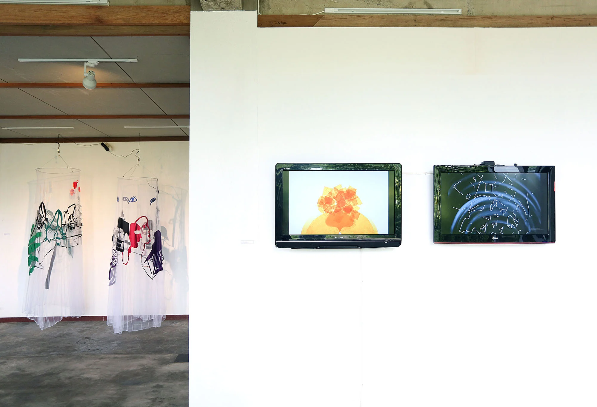 Kelambu 1 and 2, 2017, mosquito net, cotton, thread, wire, motor, 250 x 60 x 60 cm (left), Pranatamangsa, 2017, two-channel HD animation, 4:35 min loop (right). Installation view, Orbital Dago, Bandung, Indonesia, 2017.