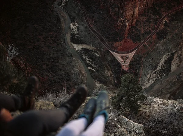 Couple's feet hanging off the edge of Angel's Landing in Zion National Park