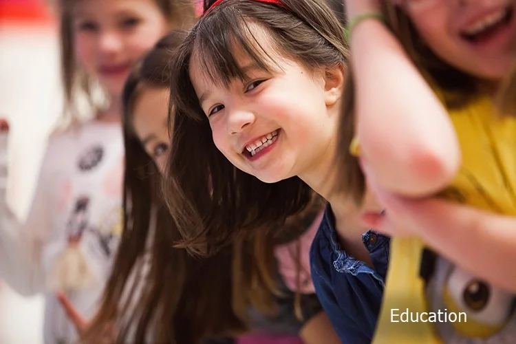 Group of children smiling and looking at the camera in a classroom setting.