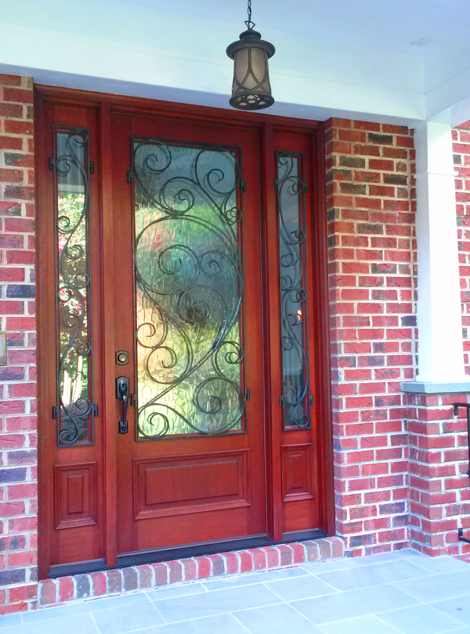 A beautiful new mahogany entry door with art glass and wrought iron detail provides a level of grandeur as one enters the porch.