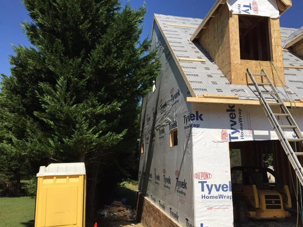 Keep the tree.  The walls and roof are up as well as the dormer.  Starting the drying in process.  Oh, and a porta potti.  Every job has to have one.  Photograph by Lloyd Dunn.