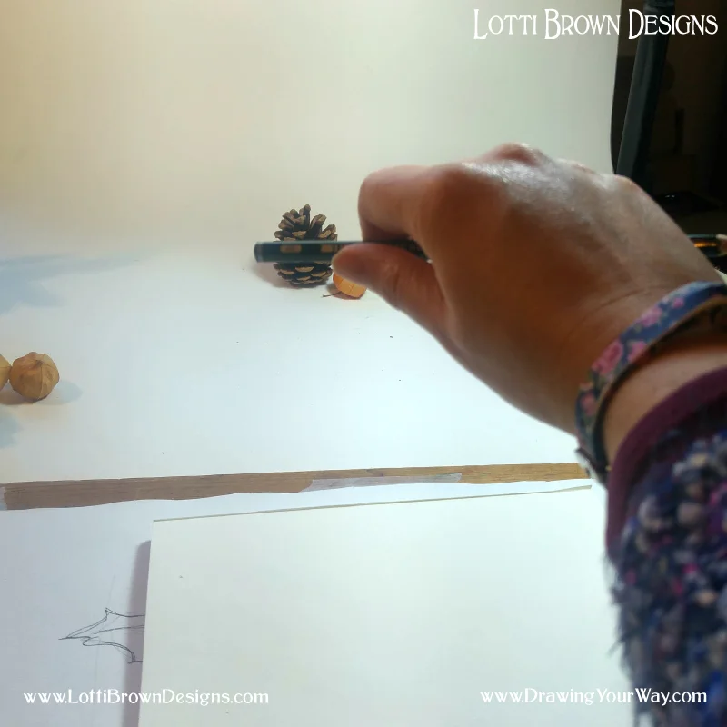 First, I check the width of the pinecone against the pencil and use my thumb to mark the spot