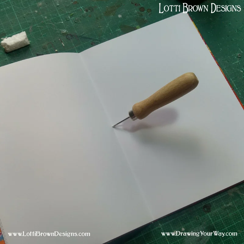 Using a bradawl to make a hole in the centre of the sketchbook