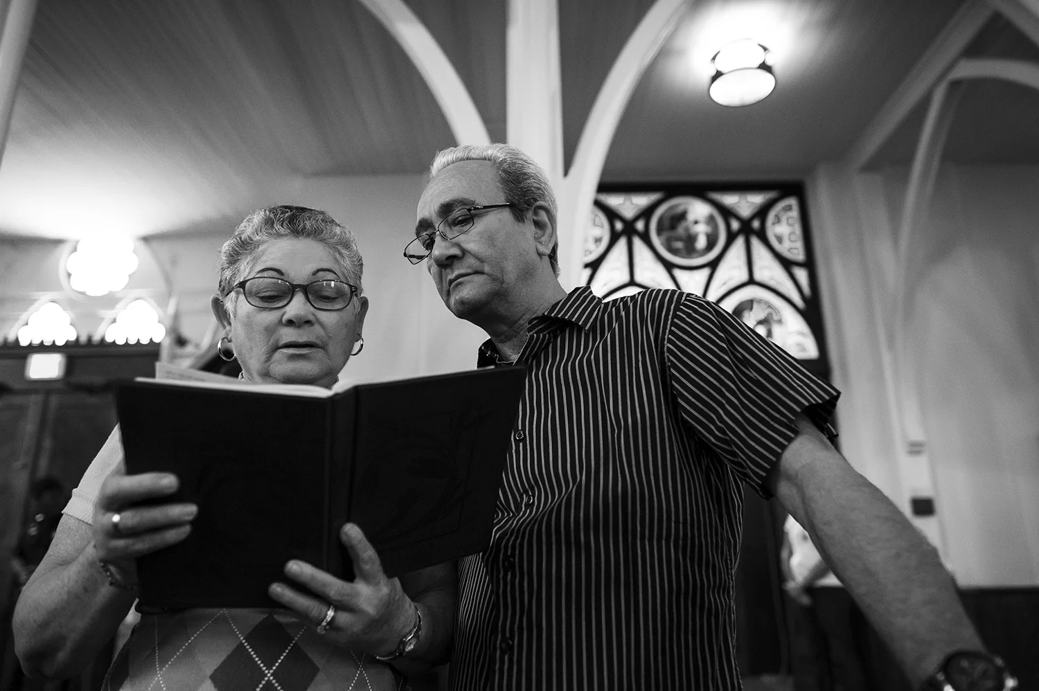 Abdel and Alina are a Cuban couple living in Bowling Green, Kentucky, though living is proving difficult. They do not speak english, they eat on $107 a month in food stamps, they reside in Bowling Green Towers, paid for by the government, and have an array of cardiac, pulmonary and spinal problems between them. Before their problems, the first thing they would tell you is how much they have to thank God for their new life in America. They look past the trouble and recognize what relief they have received from escaping working for the Cuban government and still having each other. Abdel and Alina follow along in the Bible with the mass at St. Joseph's Catholic Church.