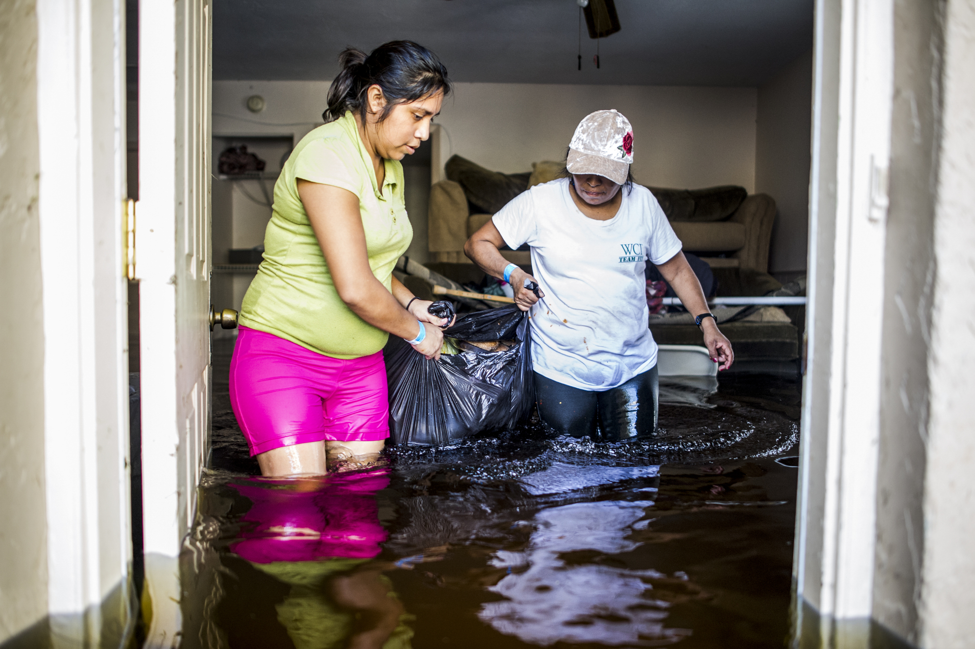 Nayeli Vasquez, left, and her aunt, Basilica Ventura, right, carry the last salvageable valuables out of their flooded home in Bonita Springs.