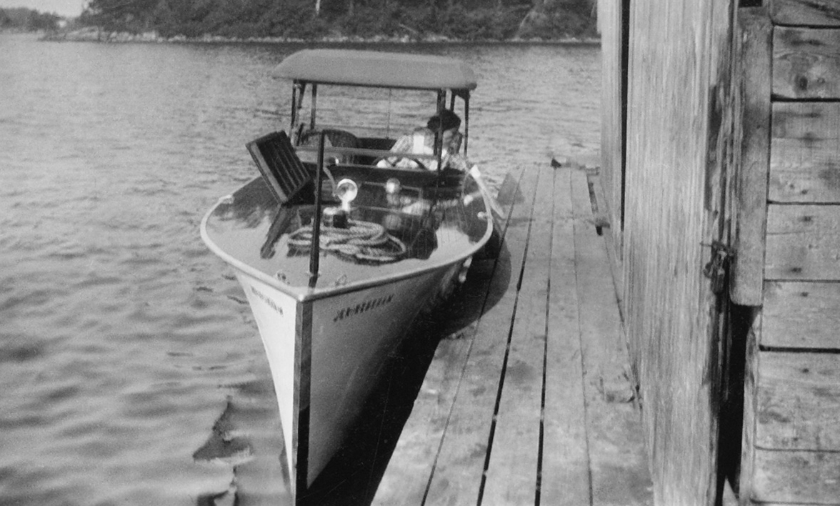 In 1942, Hamilton Davis wrote a postcard to his niece, Frances Davis, telling her he had sold the hotel that he loved so much. Standing on a Pointe au Baril shoal, Hamilton (top, at right) poses with Albert Desmasdon. Irene Davis (above) at the helm of her launch, Jerireneham . The name incorporated the names of her family: Irene, Hamilton, and their son, Jerry, who died at the age of five. 