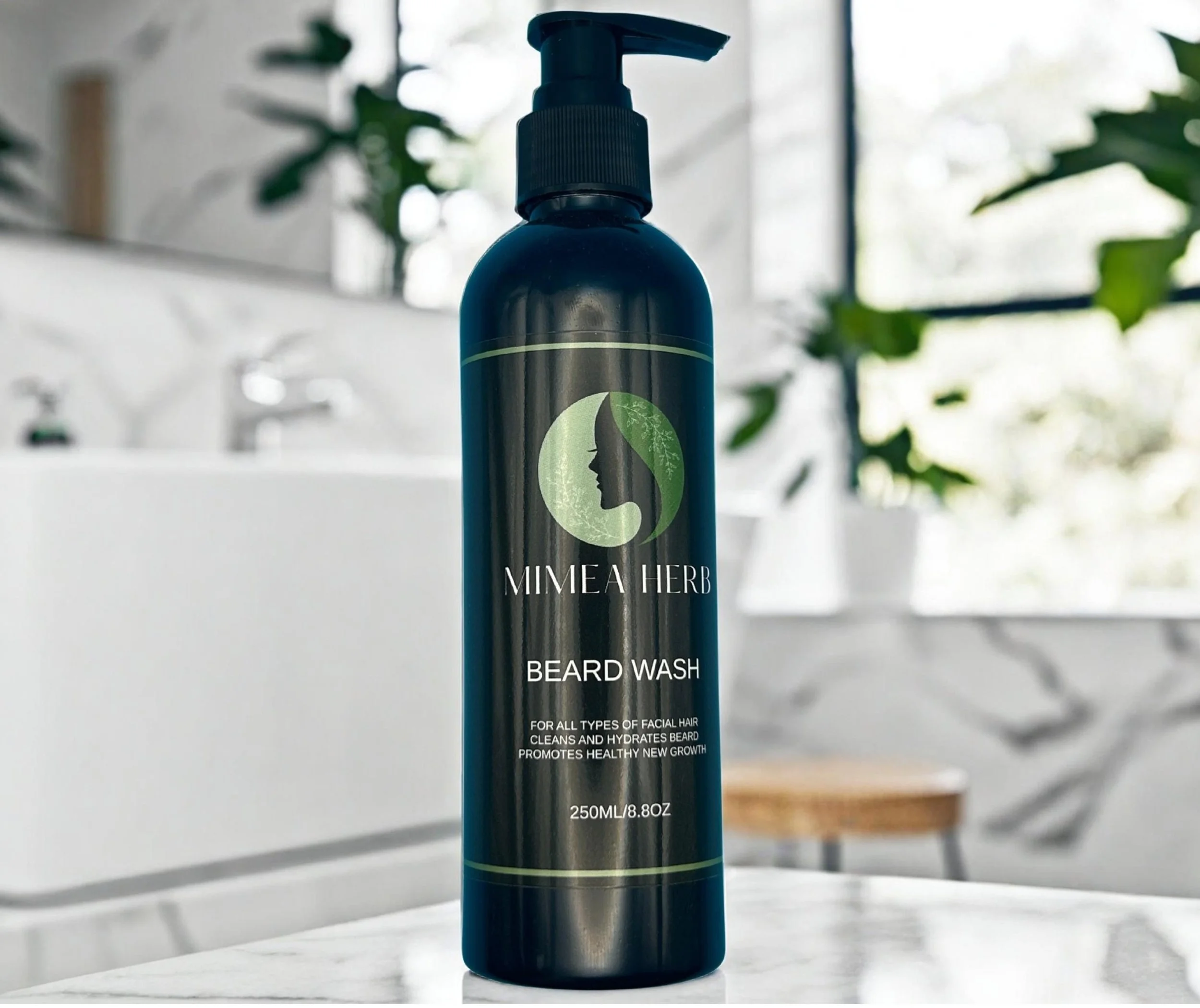 A black bottle of Mimea Herb Beard Wash with a pump dispenser on a white marble surface, in a bathroom with white brick walls, a white sink, green plants, and a window in the background.