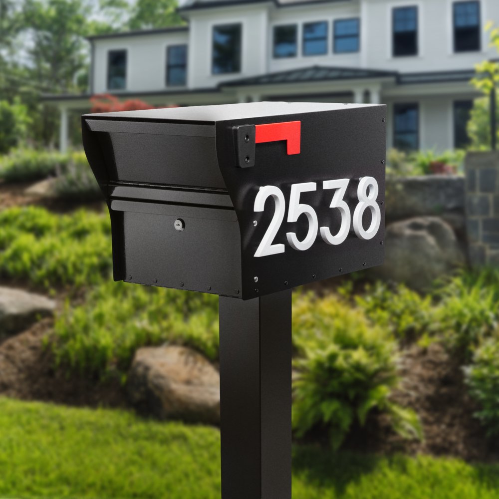 A black mailbox with the number 2538 on it, mounted on a black post in a landscaped front yard of a house.