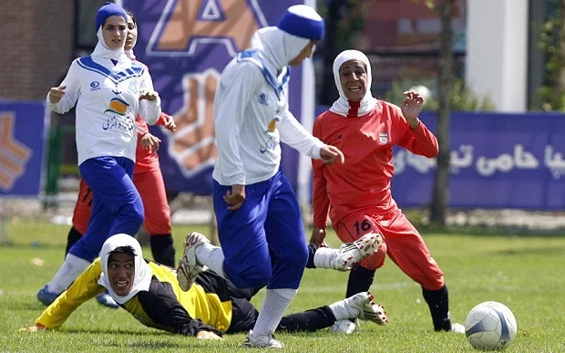 Iran’s “women” national football team (red and yellow) play a friendly football match with club Malavan Anzali football team in Tehran; Source: The Telegraph , Photo: Getty Images