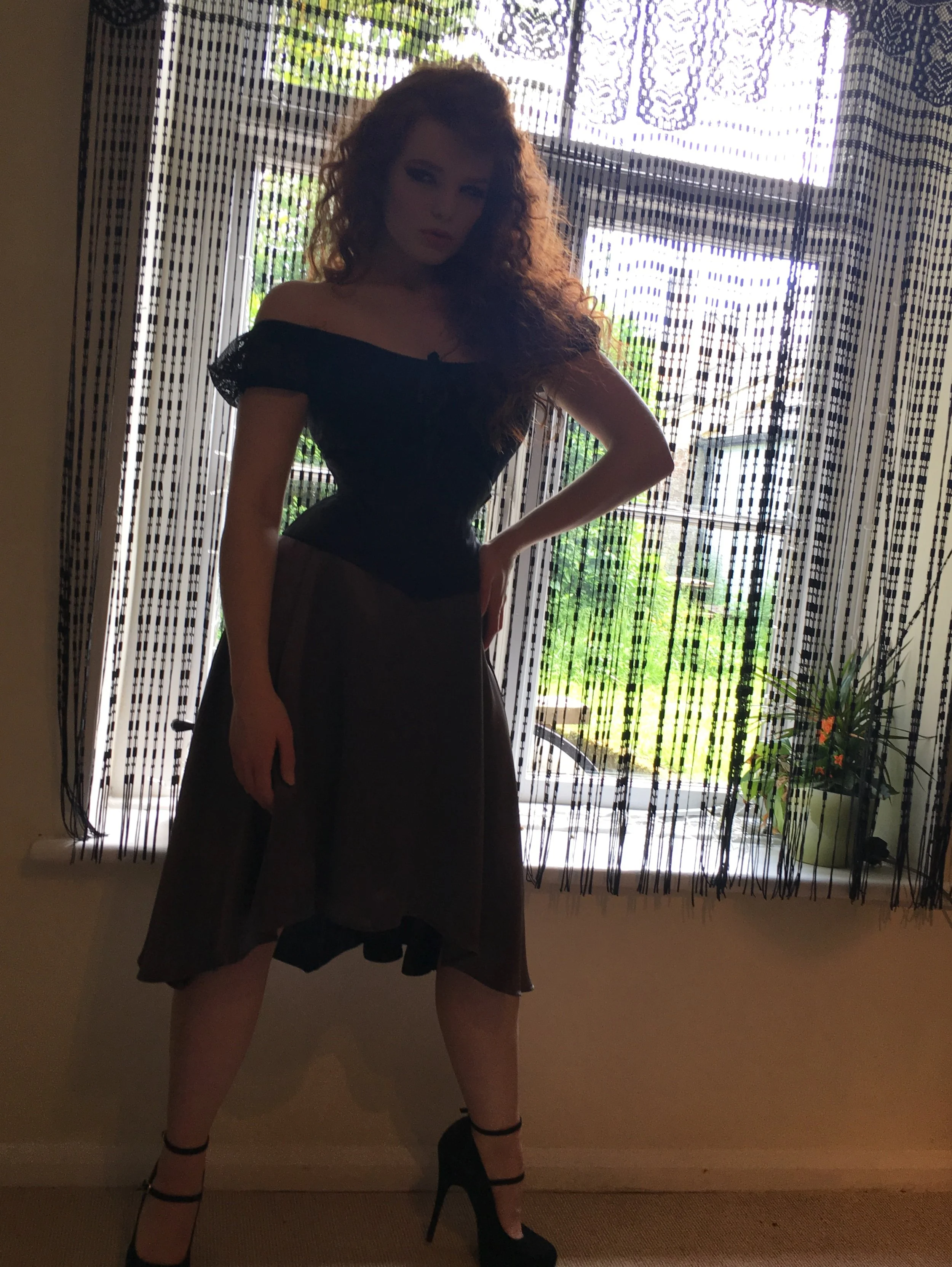 A wasp waisted femme fatale wearing an hourglass cincher by JB Corsets