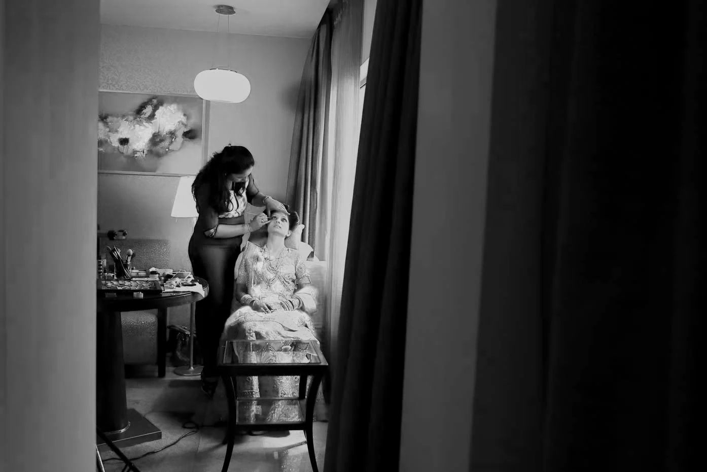 Bride getting ready in a room as the make up artist works on her eyes