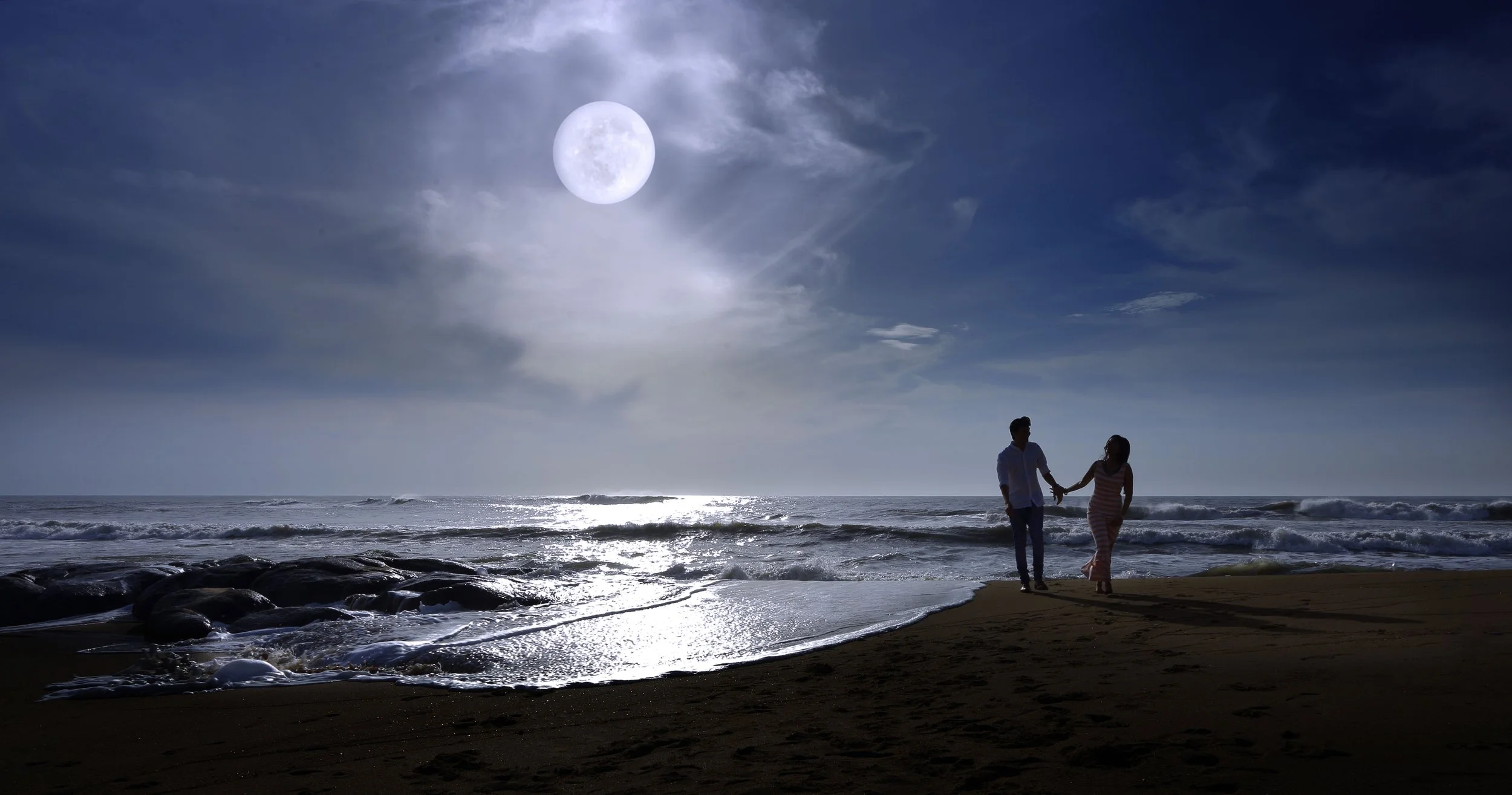Silhoutte of couple with moon lit sky and sea in the background during a prewedding shoot