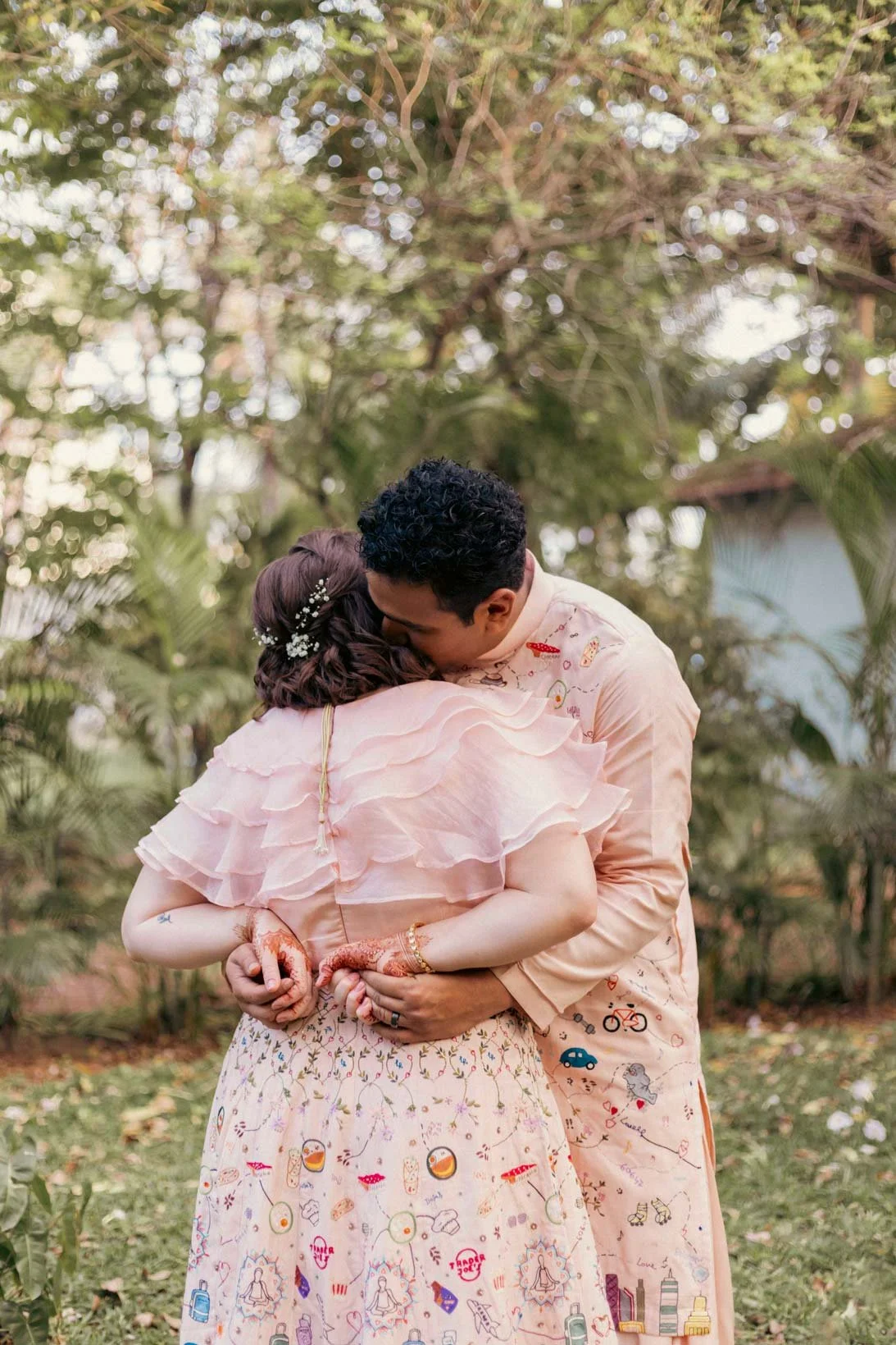 Photo of a couple in a lush green background and they hold each other