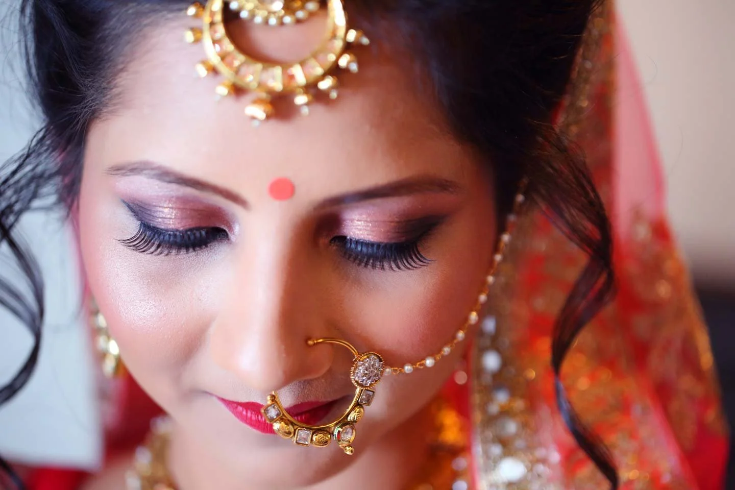 Close up of bride with gorgeous make up detail and bridal ornaments in traditional north indian wedding clothes