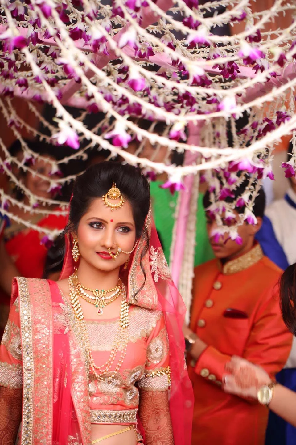 Bride enters as she  her family surrounds her surrounded by flowers
