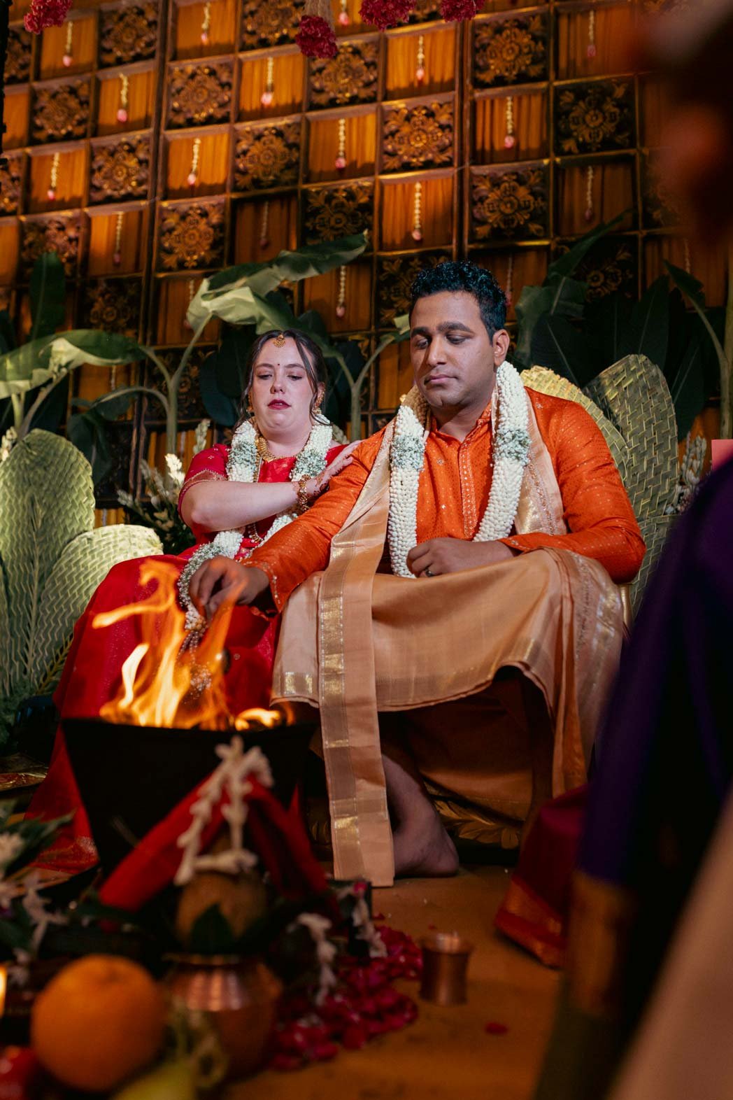 South Indian bride and groom sit in front on the sacred fire performing south indian wedding rituals