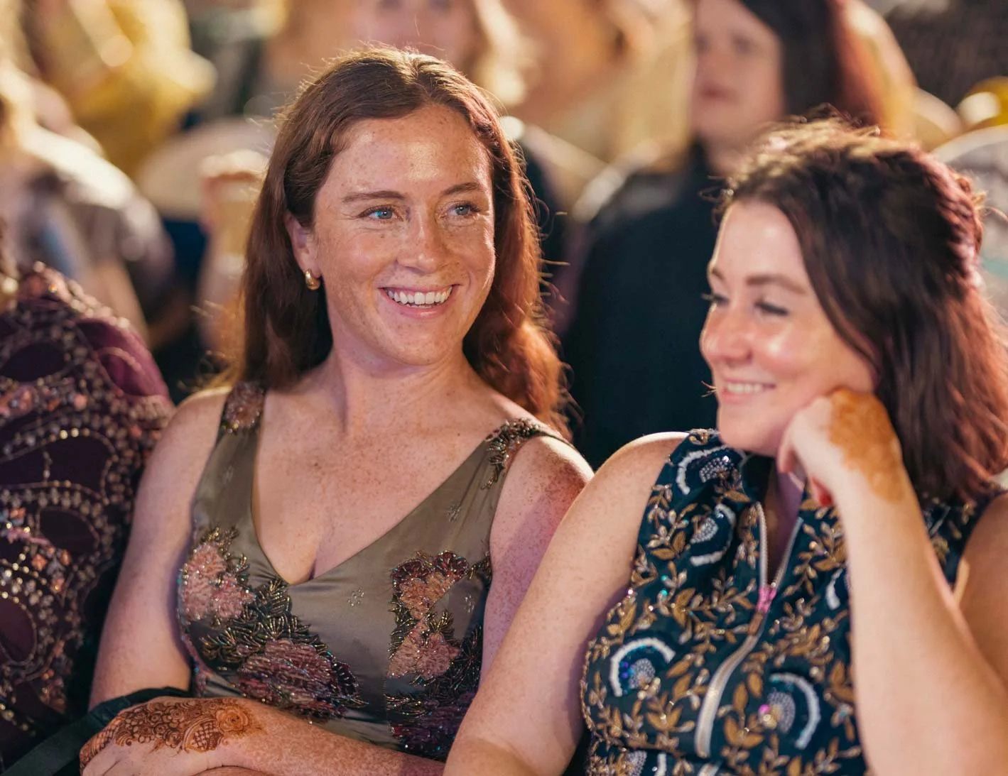 Candid photo of a lady as she looks on and smiles during Sangeeth dance performance of the groom with his friends