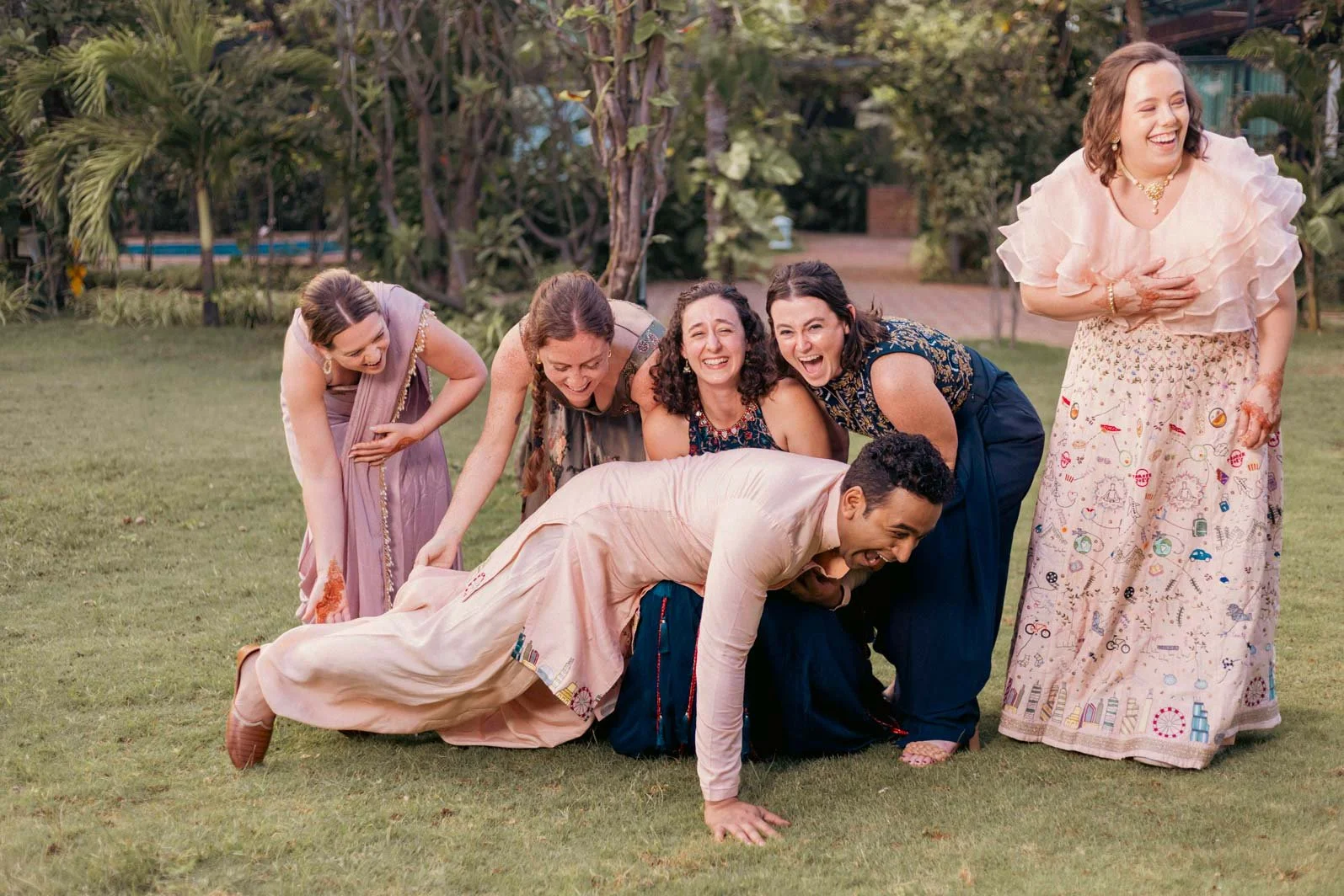A candid group picture fail moment as the bridesmaids drop the groom in this Indian Wedding bride and groom group picture