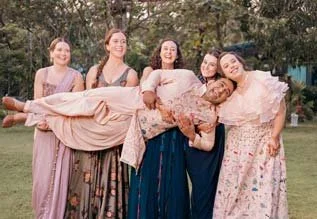 Bridesmaids lift up the groom for a fun group photo of the couple  during their sangeeth