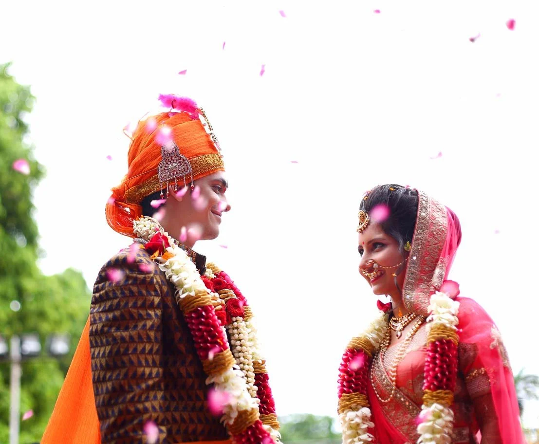 Bride and groom share a quick glance in a sweet candid moment during the garland exchange