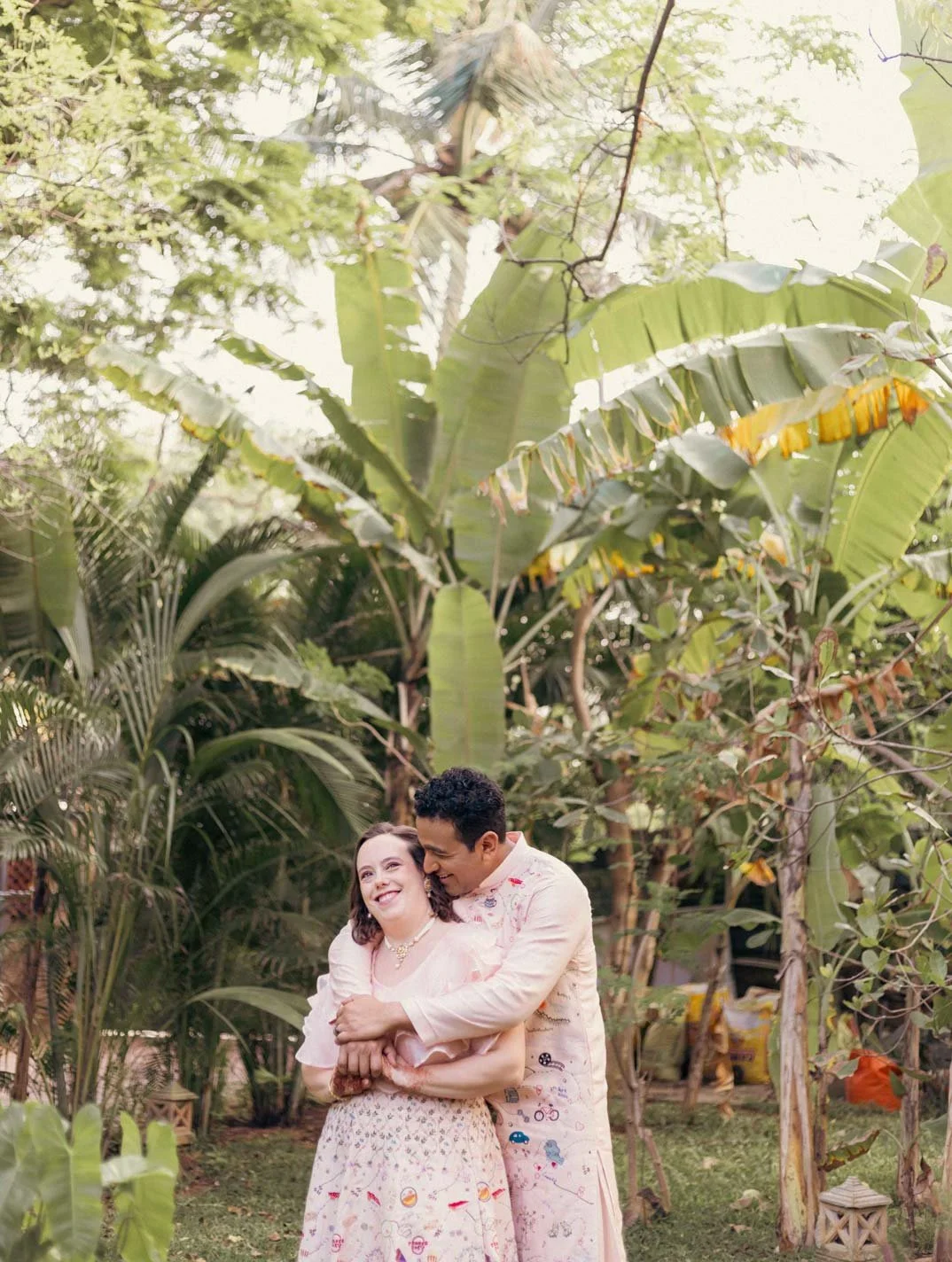 Portrait of a couple in a lush green background and they hold each other