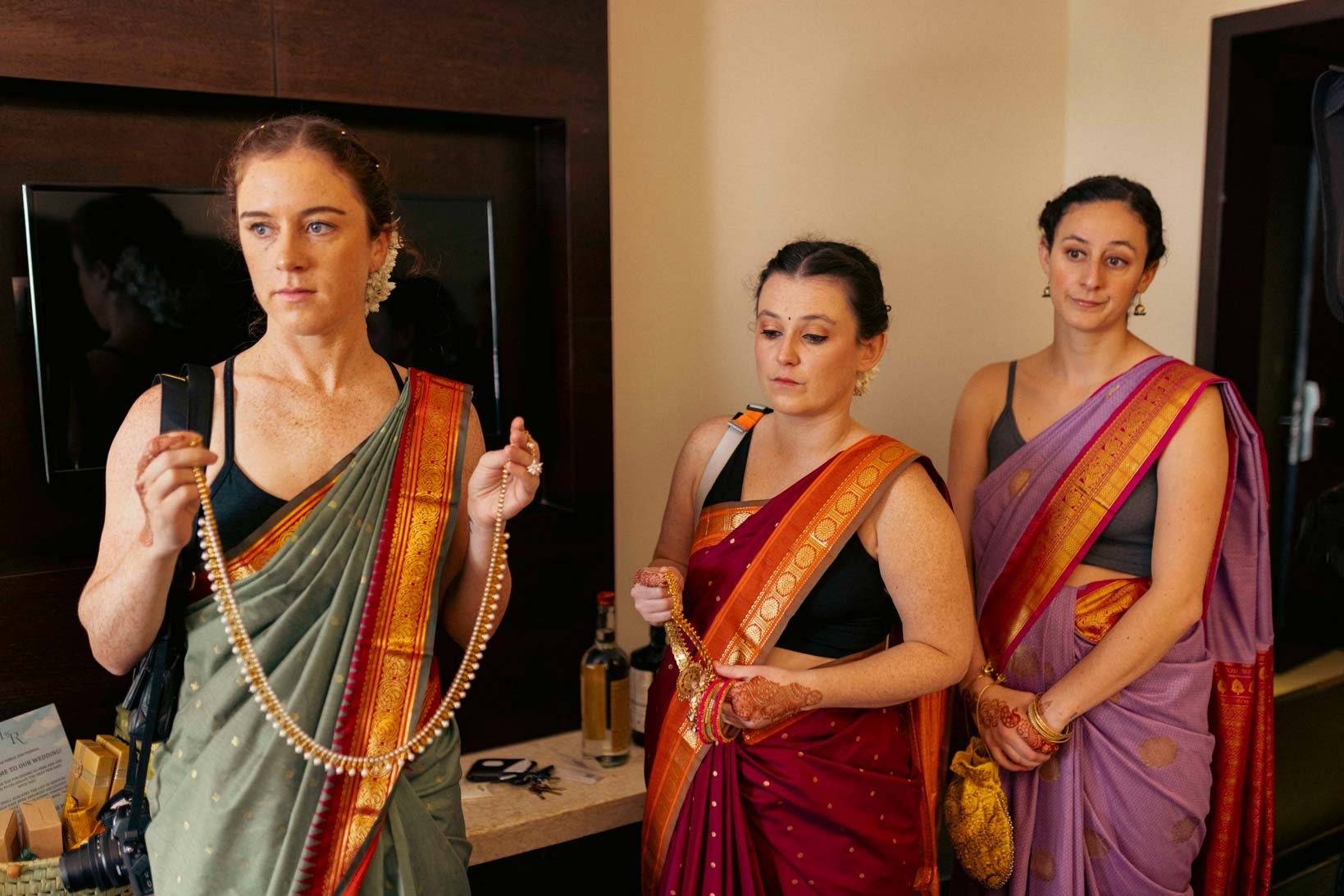 Bridesmaids of the American bride wait with her  traditional Indian jewelry as she gets ready  for her South Indian wedding ceremony