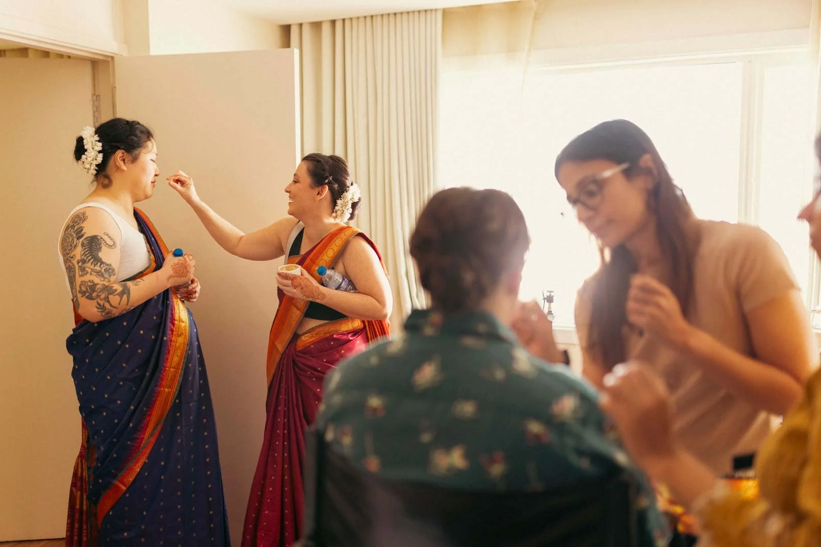 American bride gets ready for her indian wedding as her friends discuss in the background