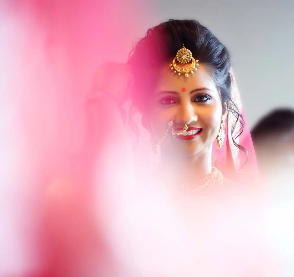 Traditional Indian bride smiles at her reflection as she gets ready for her wedding