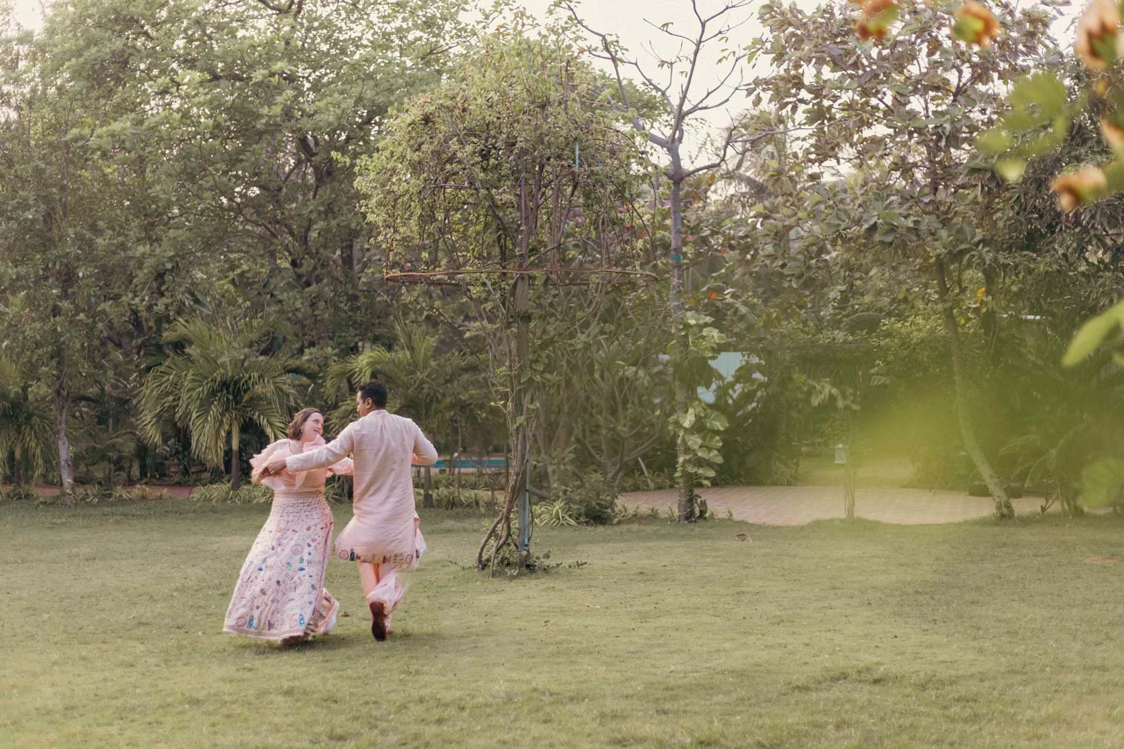 Candid Photo of a couple in a lush green background dancing 