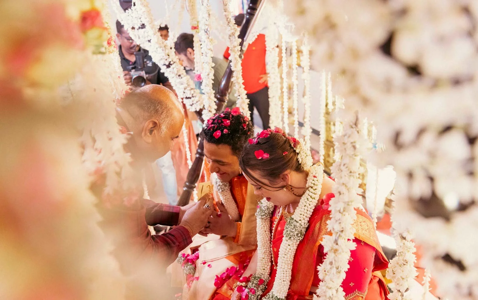Candid moment as elderly guest greets and blesses groom and bride in traditional oonjal ceremony in Indian Wedding