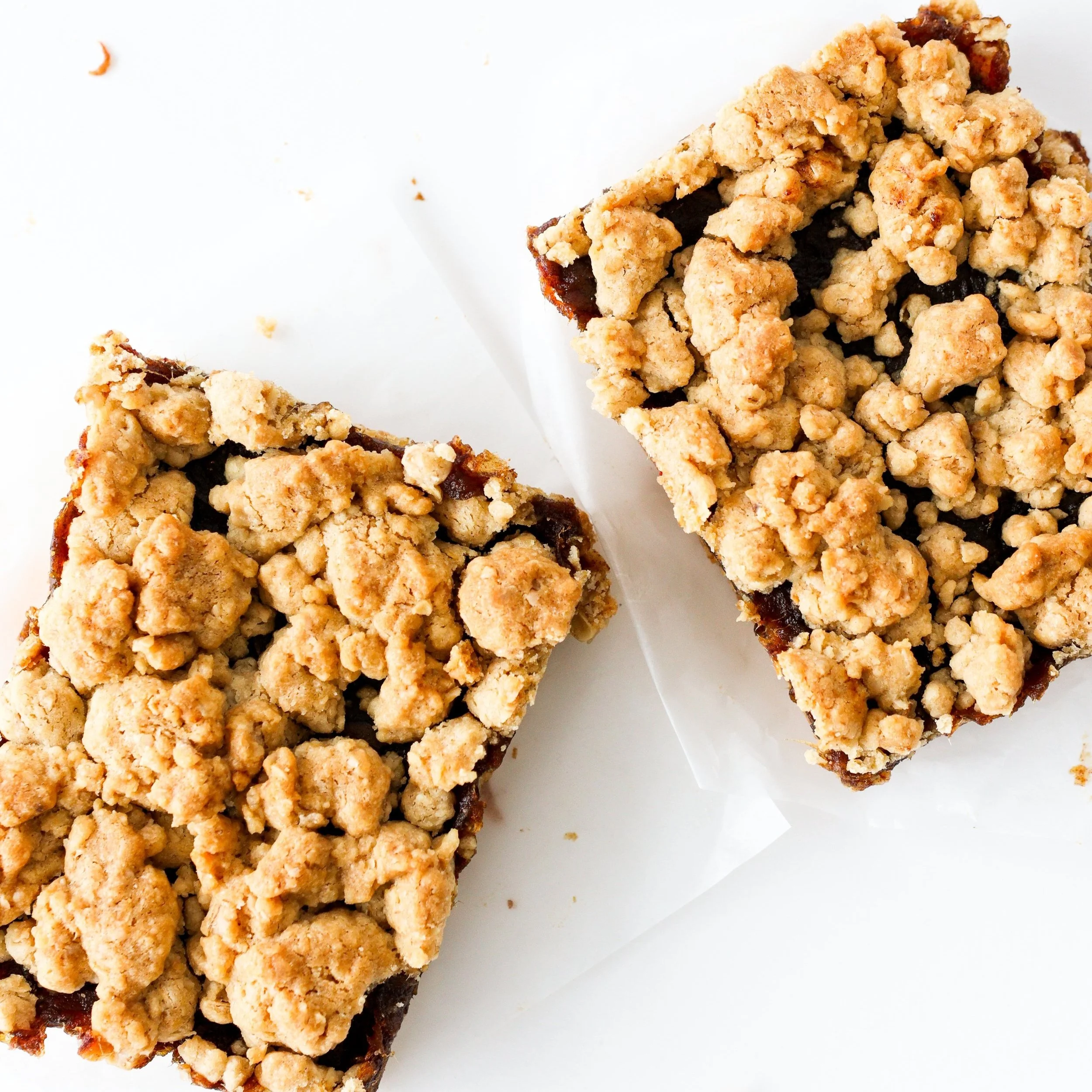 Two crumb-topped fruit bars on white parchment paper