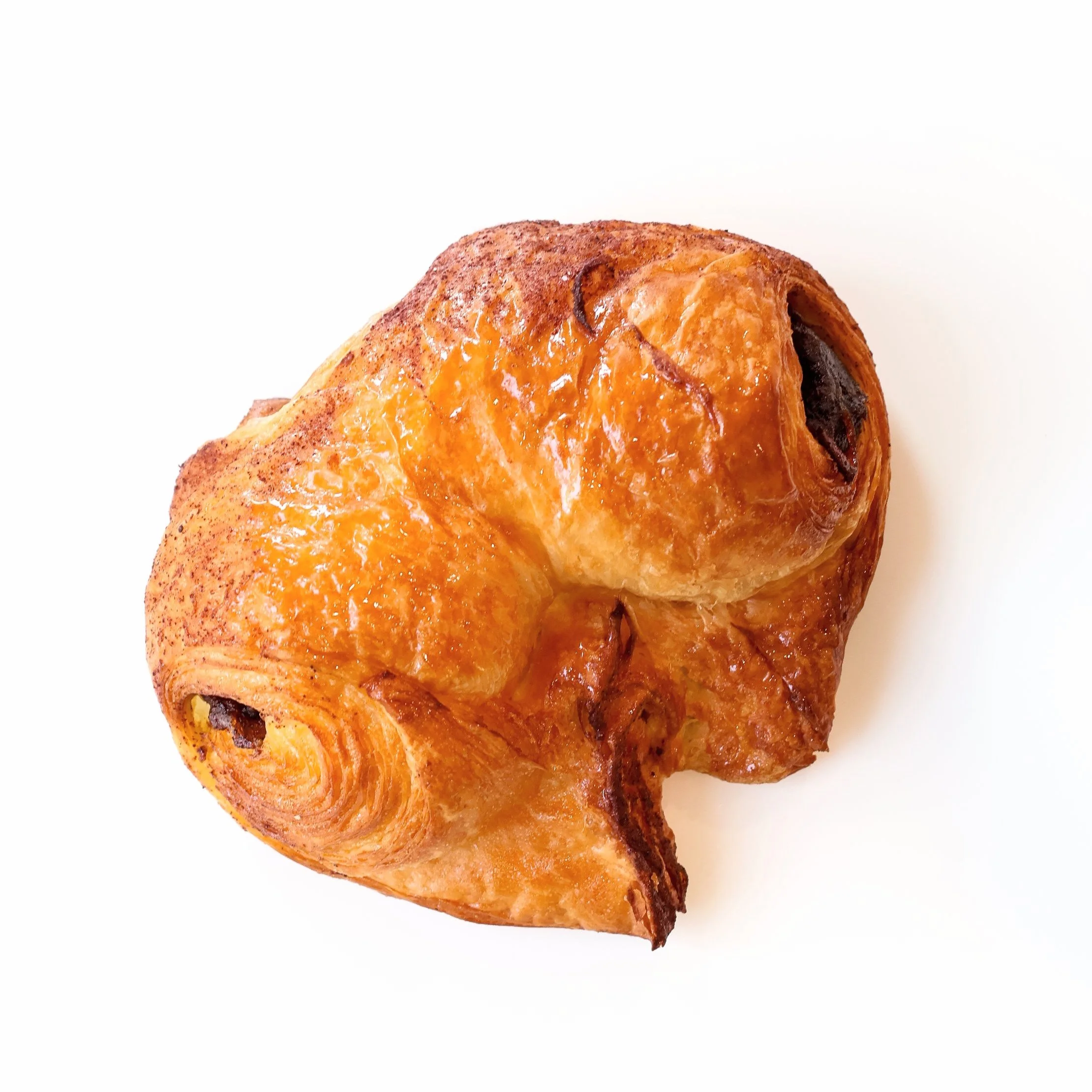 Close-up of a freshly baked croissant with chocolate filling on a white background.