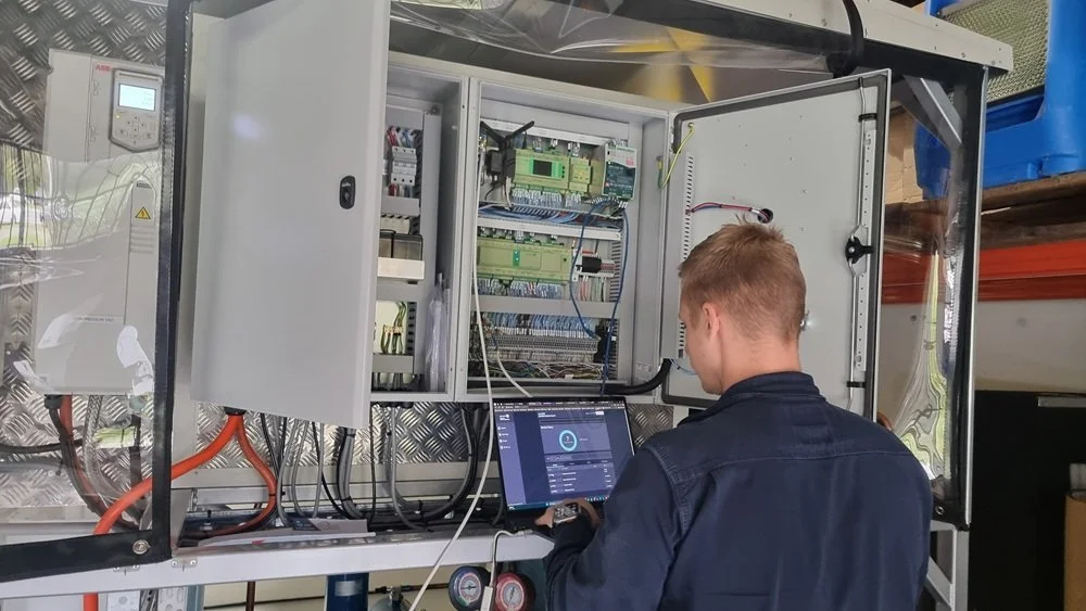 Technician using a laptop to configure controls and remote monitoring for an industrial dehumidification system.