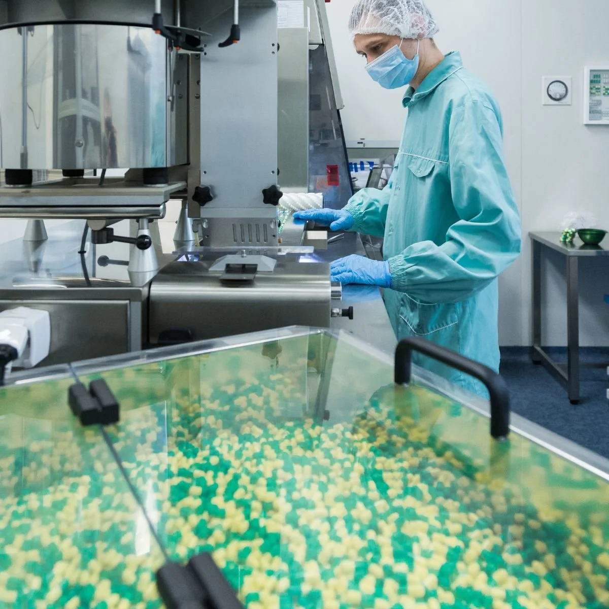 Pharmaceutical production room with technician and tablet manufacturing equipment