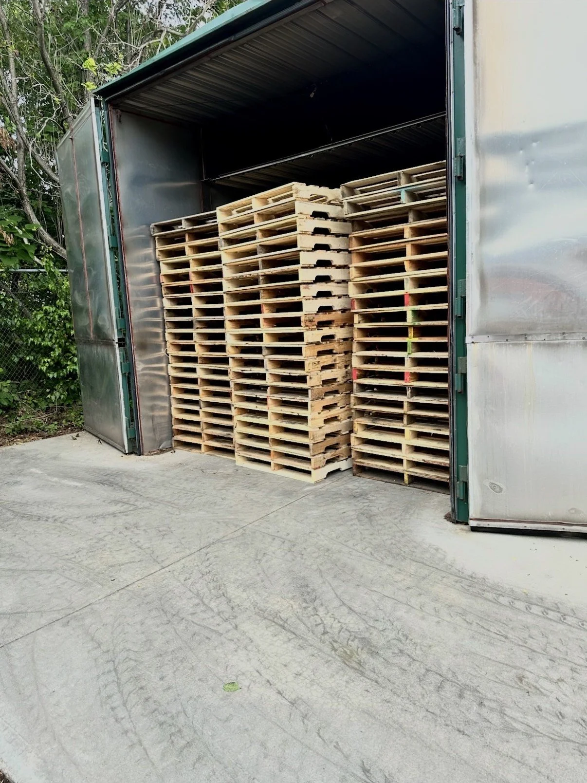 Stacked wooden pallets loaded inside a large metal storage unit or trailer.